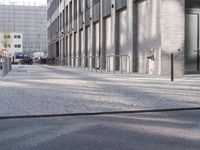 a sidewalk near a building with an umbrella near by in the sunlight at dusk with sunlight streaming in the windows