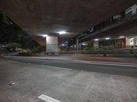 an empty street under a bridge at night with buildings in the background in china town