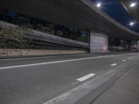 empty road underpass at night with city lights on it's sides and a dark sky above