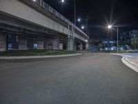 street lights are lit up on an empty asphalt road in the city at night time