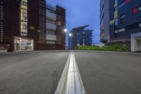 empty road with buildings in the back and lights on in the distance, with no people walking around