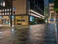 a large brick sidewalk with a store front at night time and a sign that says