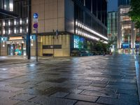 a large brick sidewalk with a store front at night time and a sign that says