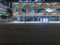 an empty street near a building at night with no traffic lights in the foreground
