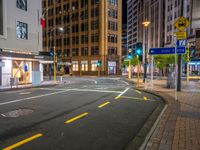 a corner in the middle of a city street at night with a traffic light in the foreground