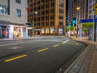 a corner in the middle of a city street at night with a traffic light in the foreground