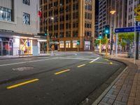 a corner in the middle of a city street at night with a traffic light in the foreground