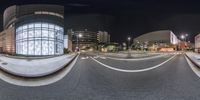 360 - view of an intersection in the middle of a city at night, as seen from below a traffic light