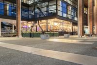 a view from outside of the building as people walk on it at night of a shopping mall with a large canopy