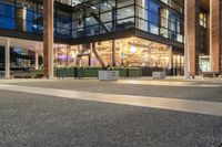 a view from outside of the building as people walk on it at night of a shopping mall with a large canopy