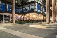 a view from outside of the building as people walk on it at night of a shopping mall with a large canopy