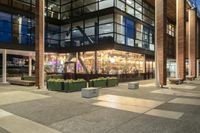 a view from outside of the building as people walk on it at night of a shopping mall with a large canopy