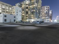 the empty lot is illuminated in the dark at night time in a city setting, with buildings on each side