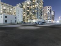 the empty lot is illuminated in the dark at night time in a city setting, with buildings on each side