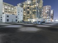 the empty lot is illuminated in the dark at night time in a city setting, with buildings on each side