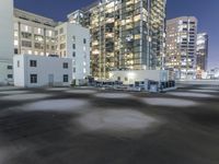 the empty lot is illuminated in the dark at night time in a city setting, with buildings on each side