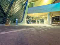 a parking space at night with light and windows lit up in the background and a car in the foreground