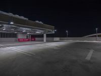 the parking garage at night showing off the red sign and it's very empty