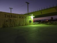 a road tunnel under an interstate bridge that reads thermal boxing club at night with the lights on