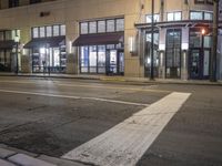 a street view of a building at night time with traffic lights on a street corner
