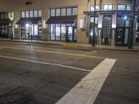 a street view of a building at night time with traffic lights on a street corner