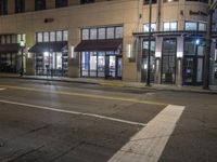 a street view of a building at night time with traffic lights on a street corner