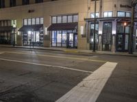 a street view of a building at night time with traffic lights on a street corner