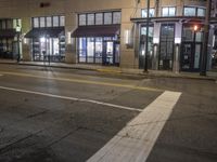 a street view of a building at night time with traffic lights on a street corner