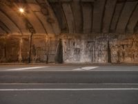 a street view with lights on and empty road in the center, with concrete wall next to highway