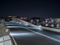 a bridge over water with buildings in the background at night time and no traffic, or people