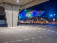 a very colorful structure lit up with lights and street lights in the city at night