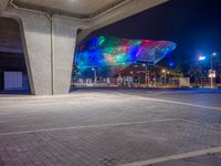 a very colorful structure lit up with lights and street lights in the city at night