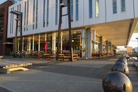 a long table and benches in front of a big building, with windows on each side