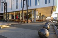 a long table and benches in front of a big building, with windows on each side