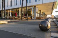 a long table and benches in front of a big building, with windows on each side