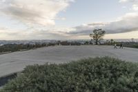 people walk across the empty parking lot in front of the mountain ranges below them are distant hills