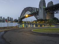 a picture from a park at the waterfront of a city with a bridge in the background