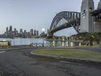 a picture from a park at the waterfront of a city with a bridge in the background