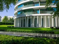 a lush green park near a two story building with a circular glass balcony at the top