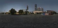 view of an empty public park in a city at night, with skyscrapers behind the square