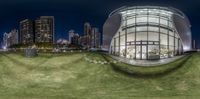 a circular mirror in the shape of an architectural structure in a city park, with a few benches and buildings and tall buildings in the background