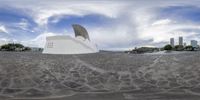 a fisheye lens picture shows there is a statue in a city park, next to the sea