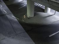 a couple walks down the street at night underneath a bridge over a roadway or road