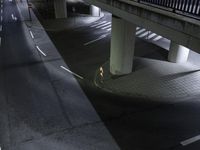 a couple walks down the street at night underneath a bridge over a roadway or road