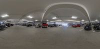 a very big parking garage with lots of cars inside of it by an arched ceiling