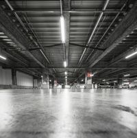 a garage with concrete floor and steel beams in black and white photo to depict urban urban spaces