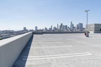 an empty parking lot with a view of a city in the background and blue sky