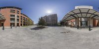 a 360 - view of a parking lot in a city near buildings and trees and the sun shining on the ground