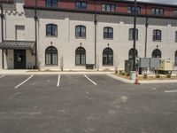 a small parking lot with a fire hydrant and some buildings with windows and pillars on it