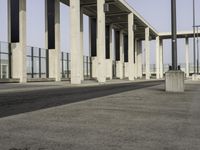 a parking lot with columns and a walkway between two building fronts that span the sky